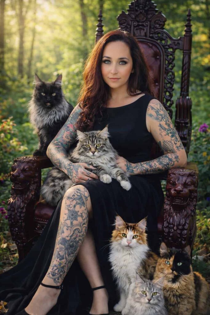Woman sitting on gothic throne with Maine Coon cats in forest setting – luxury Maine Coon breeder Utah